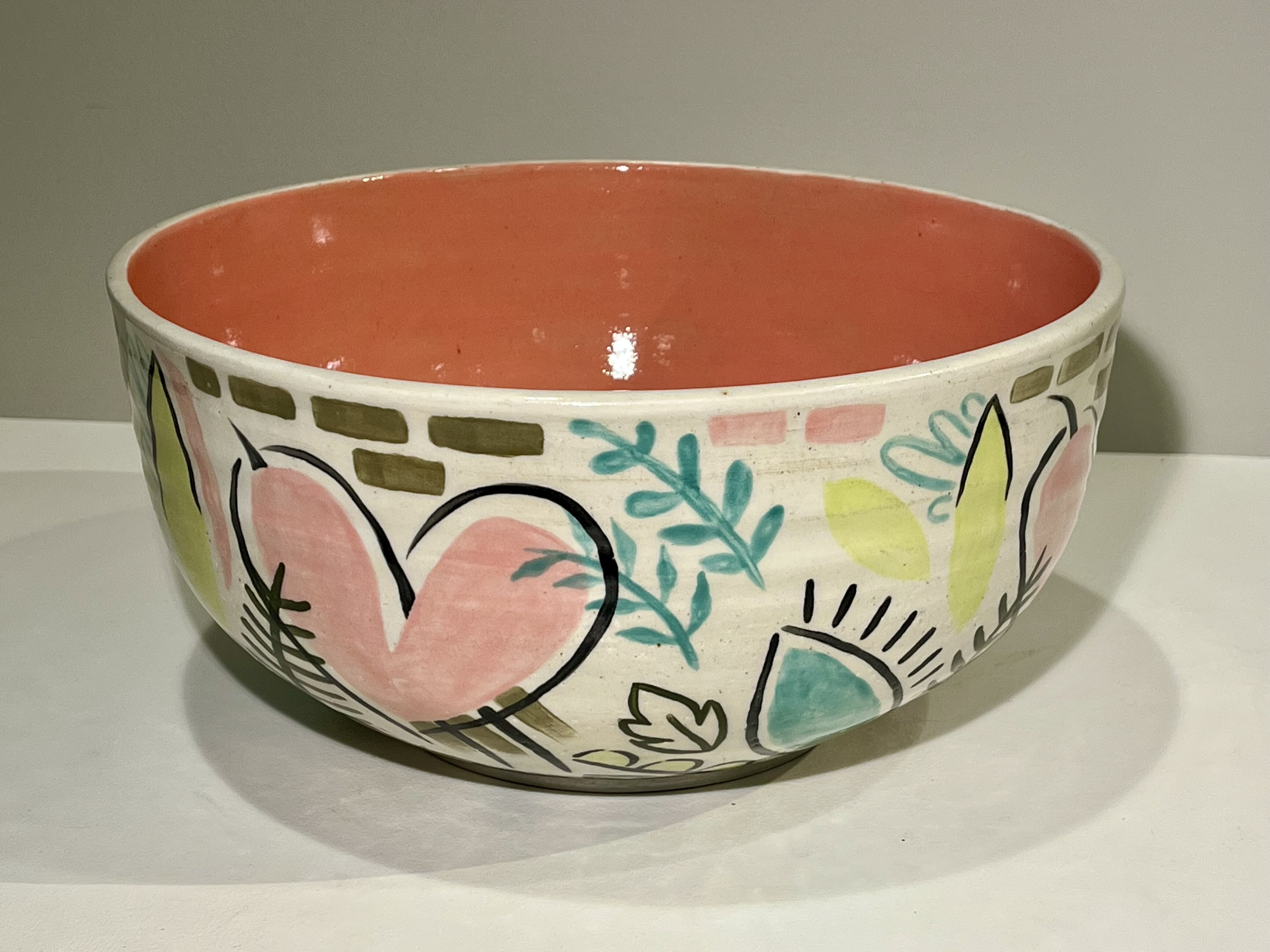 A large decorative bowl with a solid peach interior and graphic floral decorated exterior